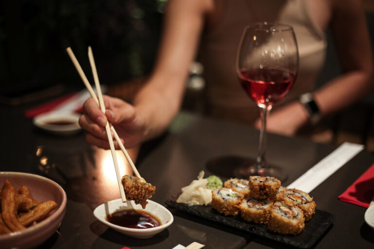 Plate Of Sushi On The Table , Woman's Hand Holding Wine Glasses in A Luxury Restaurant