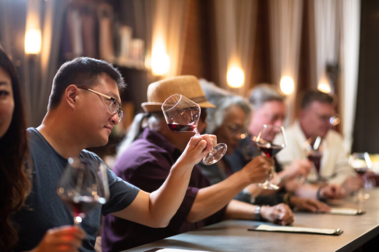 A diverse group of people sitting at the bar in an elegant wine tasting lounge in Northern California, drinking and chatting.